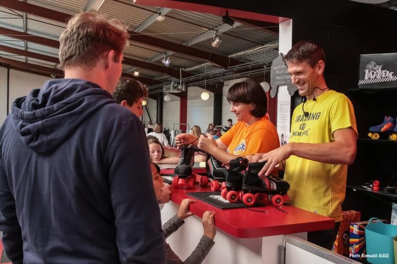 Le comptoir de location : l’équipe remet une paire de rollers à un visiteur